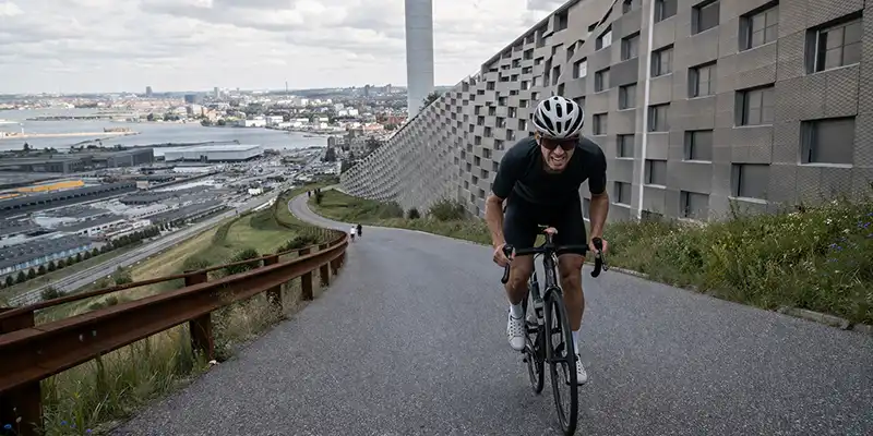 Rytter på stigning ved Amager Bakke med fokuseret indsats og tungere gear.