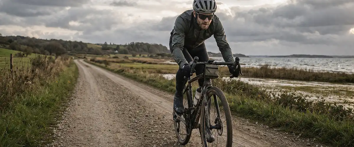 Gravelcyklist på dansk grusvej med støvet underlag, rolig natur og tydelig terrænfornemmelse.